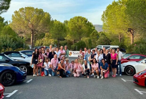 Photo de groupe des participantes entre plusieurs Porsche au départ du Rallye des Demoiselles.