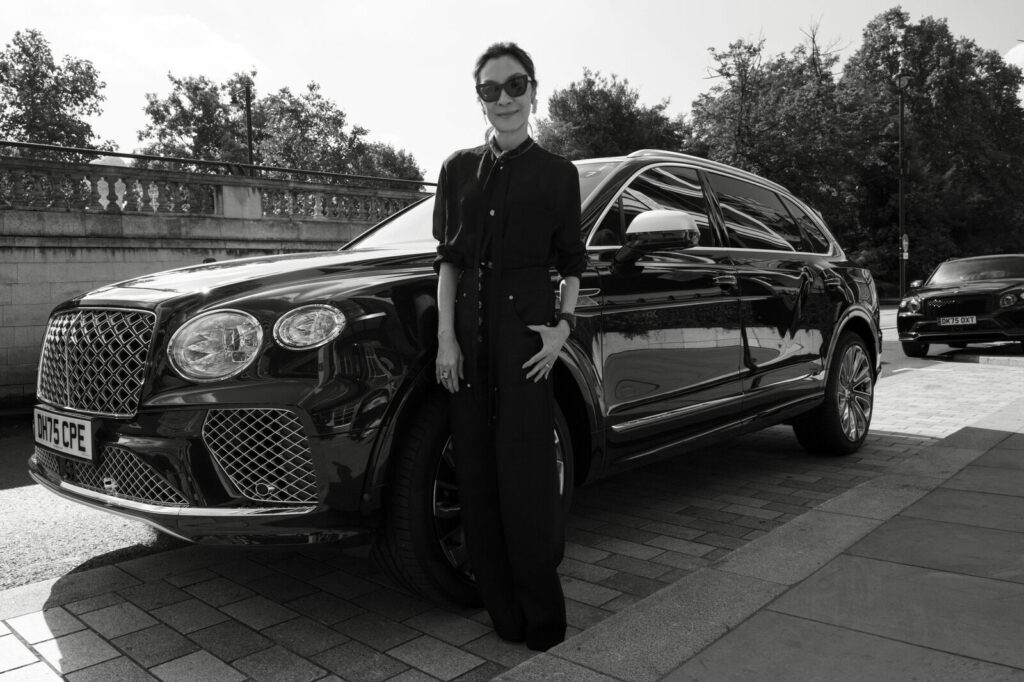 Michelle Yeoh debout devant une Bentley noire
